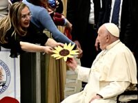 A woman presents a gift to Pope Francis during an audience to the students of the National