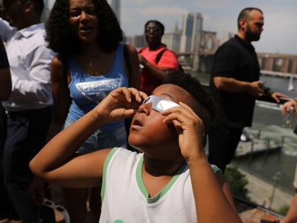 NEW YORK, NY - AUGUST 21: A child watches a partial solar eclipse from the roof deck at th