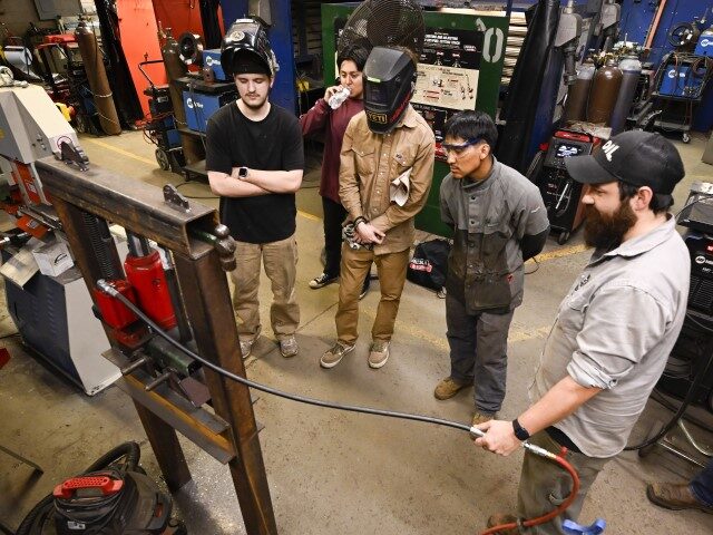 Instructor Garrett Marris, second from right, shows students a machine in operation during