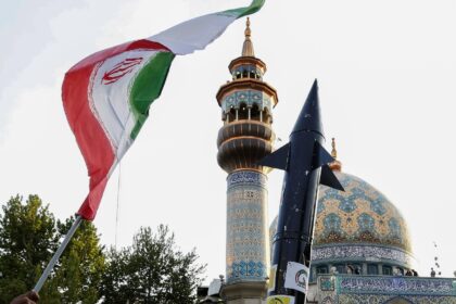 Iranians lift up a flag and the mock up of a missile during a celebration following Iran's