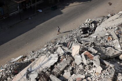 A Palestinian man walks past the rubble of buildings destroyed in Israeli bombardments, in