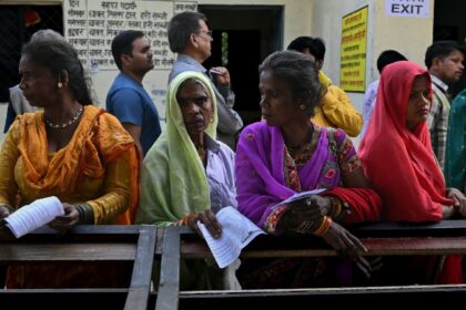 People stand in a queue to cast their votes at a polling station at Haridwar