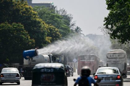 A vehicle of the Dhaka North City Corporation sprays water along a busy road to lower the