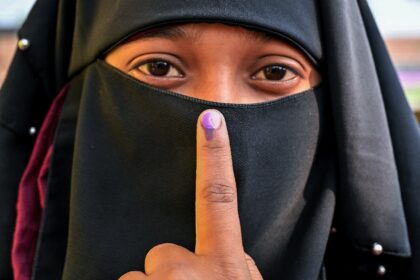 A woman shows her inked finger after casting her ballot at a polling station during the se