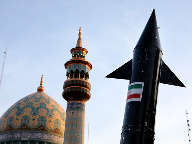 A model of a missile is carried by Iranian demonstrators as a minaret and dome of a mosque