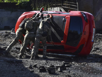 Ukrainian servicemen turn over a damaged car at the scene of a Russian missile attack in Z