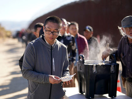 A man from China gets a bowl of oatmeal from a volunteer as he waits with others for proce