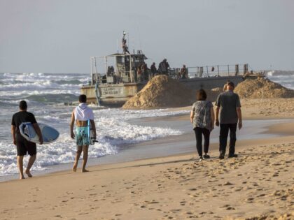 Israelis walk near a US Army vessel at that ran aground at a beach in the coastal city of