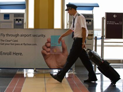 An airline pilot walks past an enrollment kiosk for the Clear Card, a frequent traveler se