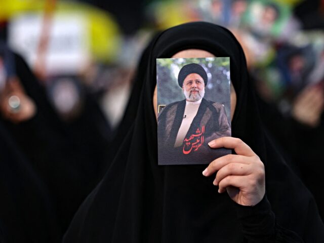 A woman holds pictures of Iran's late president Ebrahim Raisi during a rally to mourn the