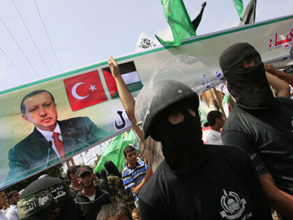 Masked Hamas militants hold a banner bearing the portrait of Turkish Prime Minister Recep