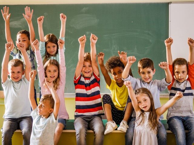 Group of happy school kids having fun with celebrating the end of school year with raised