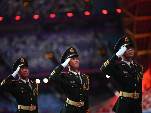 TOPSHOT - Chinese military personnel salute as China's national flag is hoisted during the