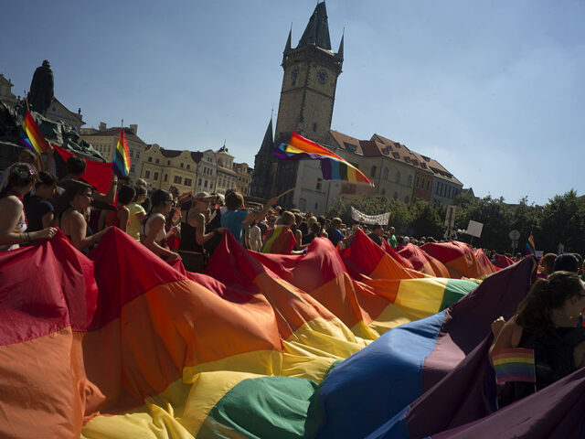 People hold up a large rainbow flag as they march across the Old Town Square during the th