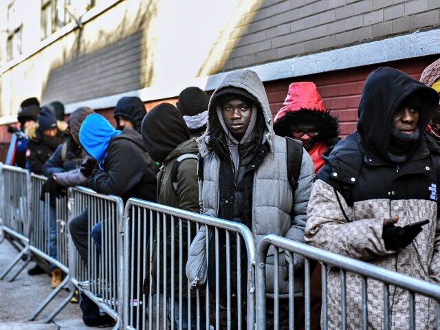 NEW YORK, NEW YORK - JANUARY 20: Homeless migrants wait in line to get a ticket for a bed