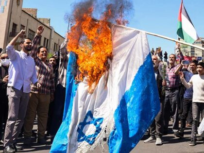 Demonstrators burn an Israeli flag during the funeral for seven Islamic Revolutionary Guar