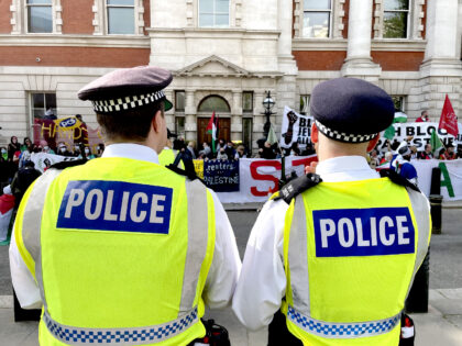 Police look on as protesters gather outside the Business and Trade department in London to