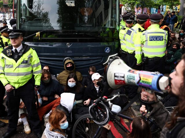 Metropolitan Police officers (MET) ask protesters to move as they gather around a bus repo