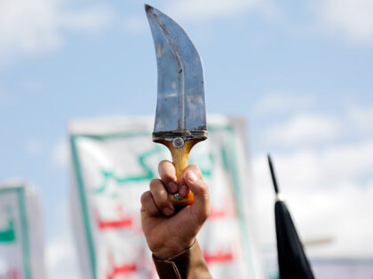 A protestor lifts his Yemen's traditional dagger "Jambya" as he participate