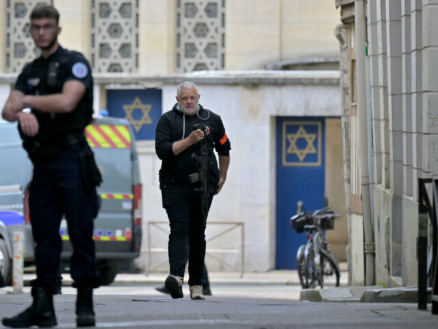 A Police officer holds a riffle as he walks by an entrance of a synagogue in the Normandy