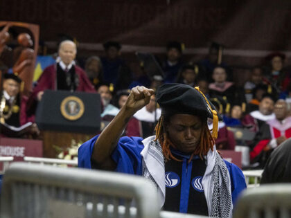A faculty member raises a fist as US President Joe Biden speaks during a graduation ceremo