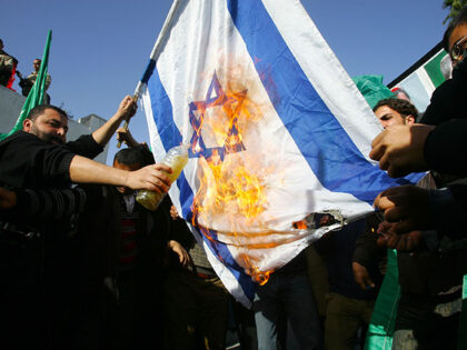 Palestinian supporters of Hamas burn an Israeli flag during a demonstration outside the de