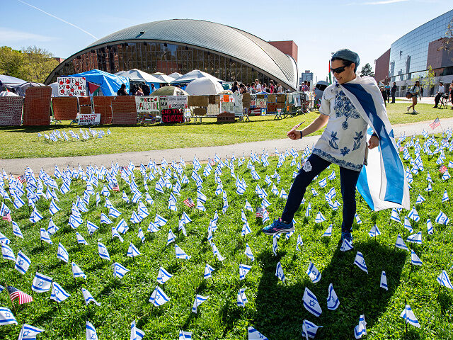 A pro-Israeli supporter plants US and Israeli flags outside the pro-Palestinian encampment