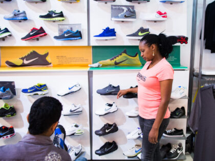 An employee, right, assists a customer selecting sports shoes at a Nike Inc. retail outlet