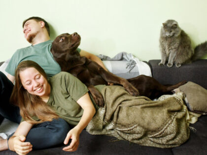 A fun couple is home with their pet dog and cat.