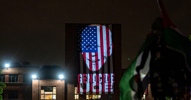 WASHINGTON, DC - MAY 3: An image of President Joe Biden with the words "Genocide Joe" are projected on an American flag that hangs from GWU Law School's Lisner Hall at an encampment at University Yard at George Washington University on May 3, 2024 in Washington, DC. Pro-Palestinian encampments have sprung up at college campuses around the country with some demonstrators calling for schools to divest from Israeli interests amid the ongoing war in Gaza. (Photo by Kent Nishimura/Getty Images)