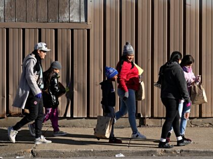 Immigrants walk down the sidewalk outside a shelter in the Pilsen neighborhood of Chicago,
