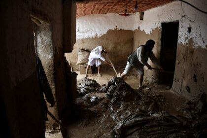 Afghan men shovel mud from a house following flash floods after heavy rainfall in Baghlan