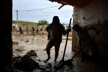 Afghans shovel mud from a house following flash floods after heavy rainfall at a village i