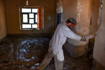 An Afghan man walks through mud in a damaged house after floods hit the Burka district of