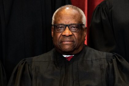 Associate Justice Clarence Thomas sits during a group photo of the Justices at the Supreme