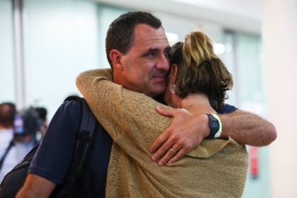 Chris Salmon embraces his wife Marney after arriving in Brisbane from New Caledonia on May