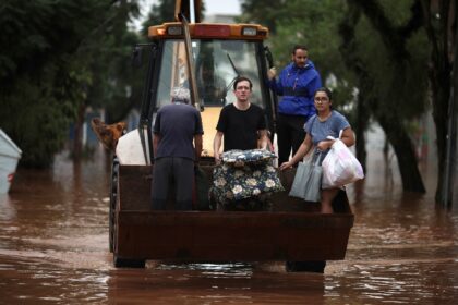 A construction vehicle carries evacuees from a flooded area of the Sao Geraldo neighborhoo