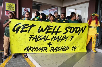 Fans hold a banner supporting injured footballers before the start of the Malaysia Super L