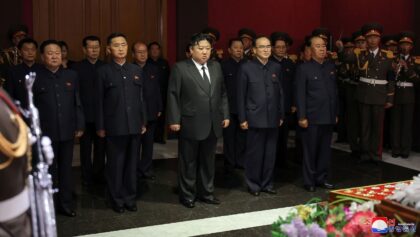 Leader Kim Jong Un (C) and senior officials pay their respects to North Korea's former pro