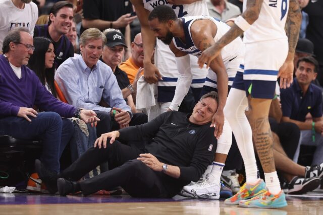 Minnesota Timberwolves head coach Chris Finch grabs his leg in pain after a sideline colli
