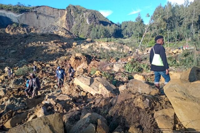 People gather at the site of a massive landslide in Papua New Guinea's Enga province on Fr