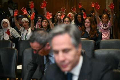 Pro-Palestinian demonstrators hold up painted hands in protest as US Secretary of State An