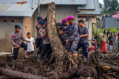 Rescue teams and people move logs that had washed into residential areas in western Indone