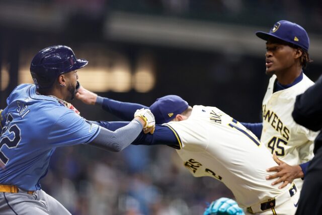 Rhys Hoskins of the Milwaukee Brewers holds back Jose Siri of the Tampa Bay Rays who attem