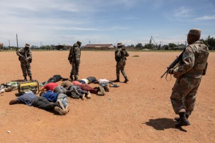 South African soldiers guard detained suspects in the fight against illegal mining in Kagi