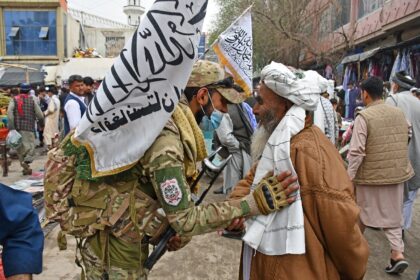 A Taliban security personnel greets a Muslim devotee after Eid al-Fitr prayers in the city