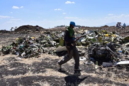 A man walks by a pile of twisted debris at the crash site of an Ethiopian Airways Boeing 7