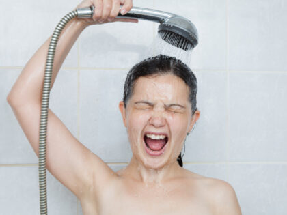 A woman takes a cold shower.