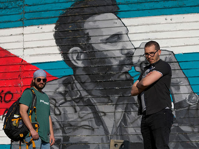 Fernando Almeyda Rodriguez, right, and Remy Hernandez, pose in front of a mural of late Cu