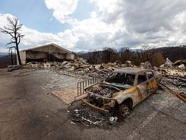 A charred car and the remains of the Swiss Chalet Hotel are pictured after being destroyed